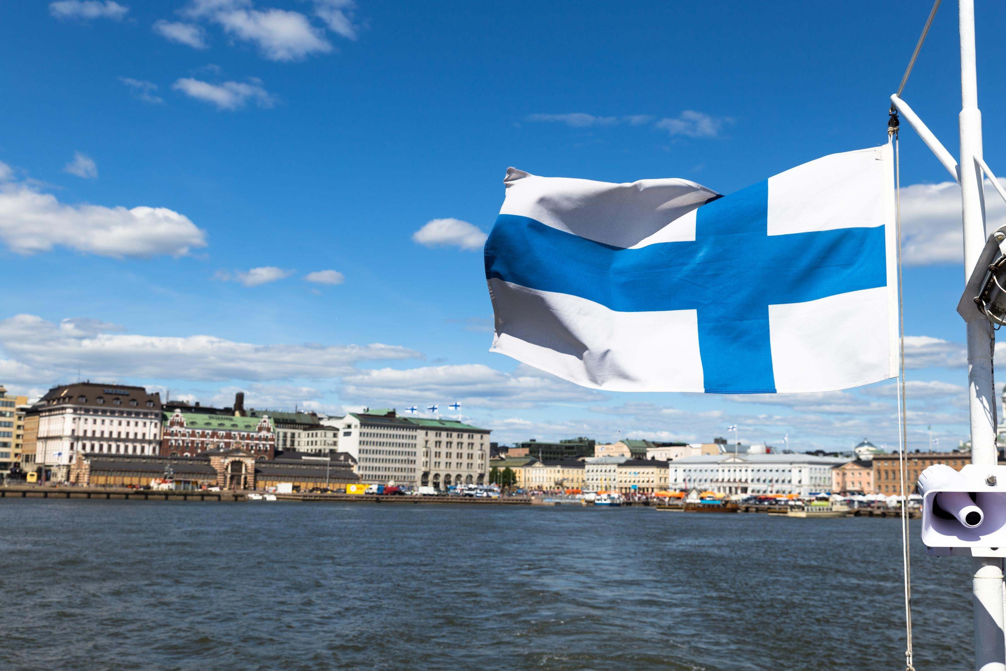 Финский флаг на фоне Хельсинки, столицы Финляндии, где оформить гражданство могут иностранцы
