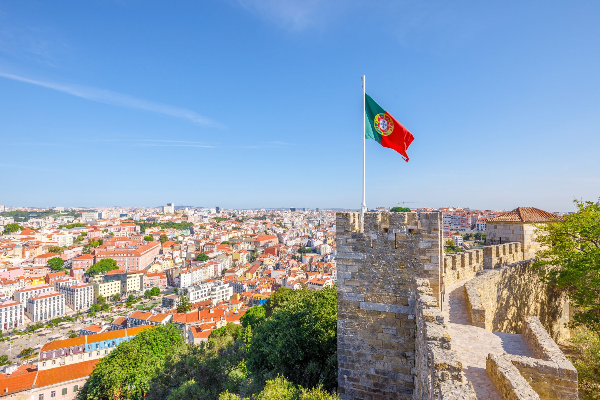 Португальский флаг на фоне Лисабона, столицы Португалии, куда иностранцы могут переехать, получив гражданство